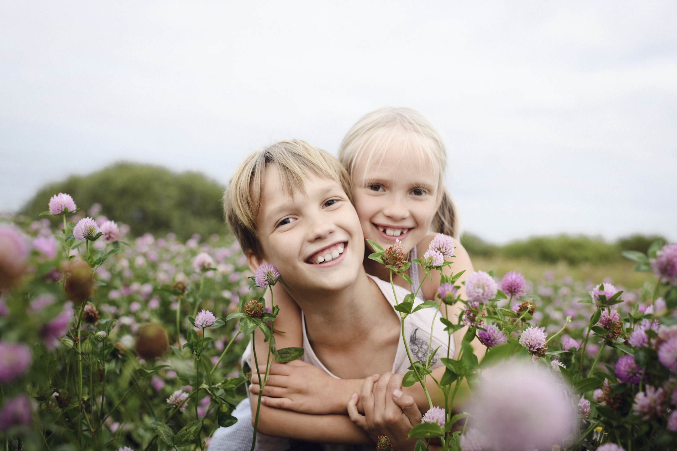 Zwei lachende Kinder sitzen auf einem Feld